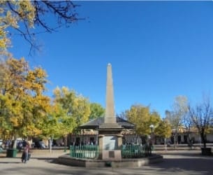 Sandia Hearing Aids Santa Fe - An obelisk in a plaza with trees in the background.